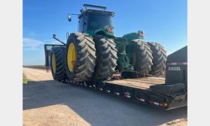 Large farm tractor with oversized tires loaded on trailer by Oden Transport.