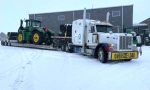 Large farm tractor being hauled on trailer by Oden Transport, with year-round services in Texas, Oklahoma, Kansas & New Mexico.